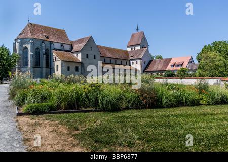 Side view of Reichenau Abbey with monastery garden according to the plans of Abbot Strabo and his writing Hortulus. The monastery gardens on the island of Reichenau are an important testimony to medieval garden culture and are closely linked to the history of the Benedictine monastery founded in 724. Two of the most important medieval sources on garden culture originate from here: the famous St. Gallen monastery plan and the poem 'Hortulus' by the Reichenau monk and later abbot Walahfrid Strabo. The monastery gardens are located near the Minster of St Mary and St Mark in Reichenau-Mittelzell.  Stock Photo