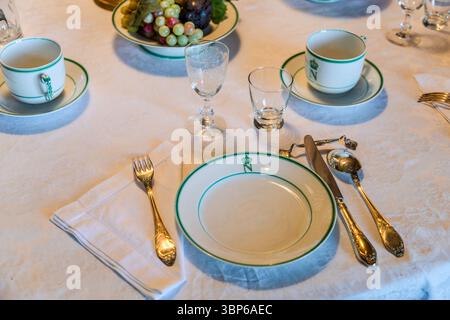 An elegantly laid dining table at Arenenberg Castle in Salenstein, Thurgau, Switzerland, displays Limoges porcelain decorated with a crowned "N" monogram, a reference to the Bonaparte family who resided here. Gold-coloured cutlery, fine glasses and a fruit bowl complete the historical ambience of a festive table. Stock Photo