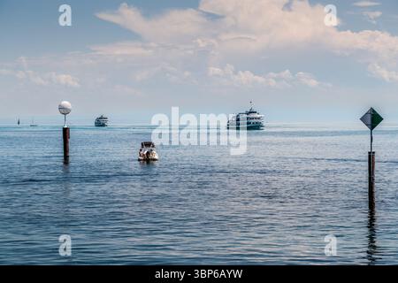 A motorboat with two people is travelling on Lake Constance. Two passenger ships and several sailing boats are also on the water. Konstanz, Baden-Württemberg, Germany Stock Photo