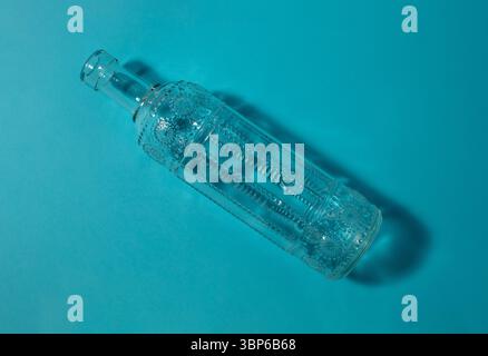 Glass bottle with embossed design on a blue background. Stock Photo