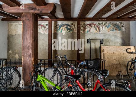 The wall of a historic room used as a bicycle parking area features frescoes. Wooden beams support the ceiling. Münsterplatz, Konstanz, Baden-Württemberg, Germany Stock Photo