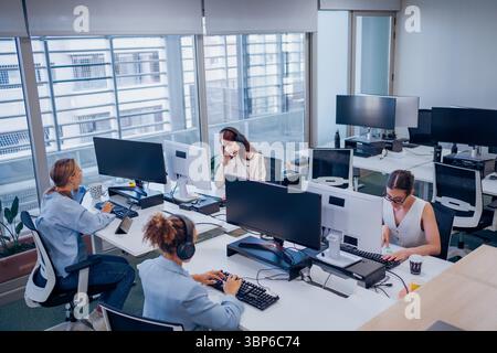 In a modern office, a diverse team collaborates effectively towards shared goals using technology Stock Photo