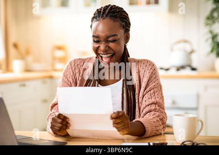 Overjoyed Black Woman Reading Letter In Kitchen And Exclaiming With Excitement Stock Photo