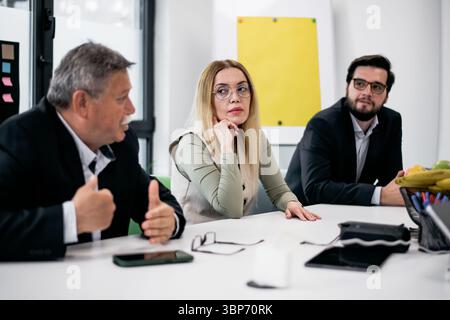 Professional setting with colleagues collaborating during a meeting, exchanging ideas and discussing strategies in an office environment. Stock Photo