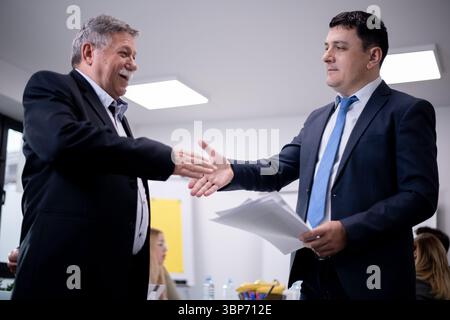 Two male professionals in formal attire exchange a handshake in a modern office, emphasizing partnership and success, with teamwork and cooperation sy Stock Photo