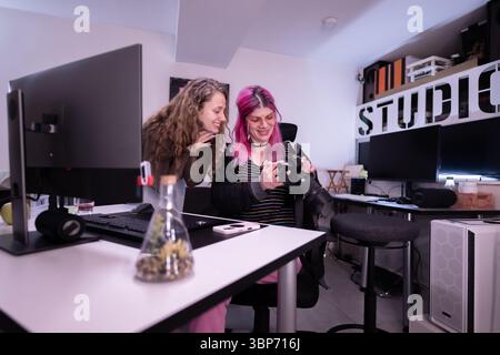 Two people are passionately reviewing camera footage in a vibrant, organized studio environment, showcasing collaborative creativity and professional Stock Photo