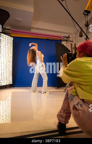 A model strikes a pose while a photographer captures the scene in a studio with colorful backgrounds and professional lighting. This image highlights Stock Photo
