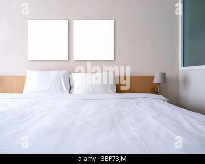 Mockup two blank square frames, 2 empty space canvas frame hanging on white wall background over wooden bed with pillows and clean blanket, decoration Stock Photo