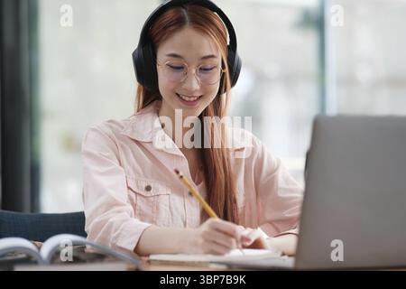 Young collage student using computer and mobile device studying online. Education and online learning Stock Photo