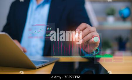 Person using laptop with glowing holographic financial charts and data visualizations, representing business analytics, market trends, and data-driven Stock Photo