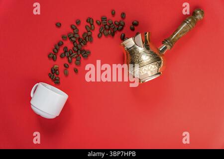 Top view of coffe beans in cezve (traditional turkish coffee pot), whte cup on red background Stock Photo