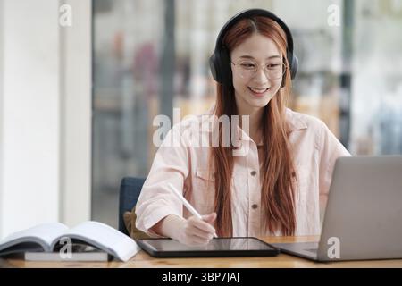 Young collage student using computer and mobile device studying online. Education and online learning Stock Photo