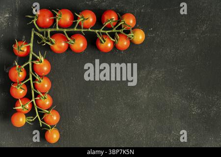 Food frame made of two branches of fresh ripe cherry tomatoes on black background. Copy space for your design Stock Photo