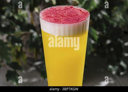 Food, Vibrant two-layered mimosa cocktail, featuring a frothy red topping, showcased on an elegant table setting Stock Photo