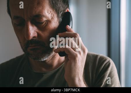 Closeup headshot portrait of adult male talking on cordless landline phone, selective focus Stock Photo