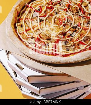 Food, A vibrant pizza featuring red peppers, mushrooms, and sauce is displayed atop a tall stack of white pizza boxes. The bright yellow background en Stock Photo