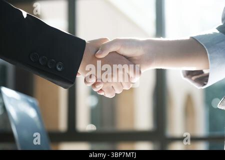 Two people shaking hands in a business setting. Scene is professional and formal. The handshake symbolizes agreement and trust between the two individ Stock Photo