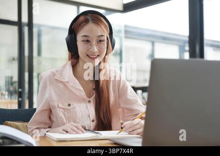 Young collage student using computer and mobile device studying online. Education and online learning Stock Photo