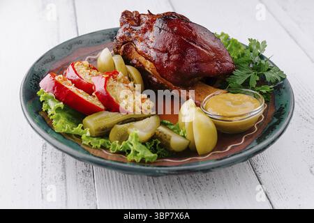 Food, Delicious roasted pork knuckle is served on a plate with sauerkraut, pickles, and mustard Stock Photo