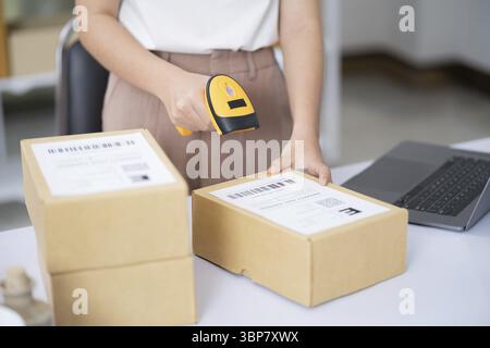 Hands scanning barcode on delivery parcel. Worker scan barcode of cardboard packages before delivery at storage. Woman working in factory warehouse sc Stock Photo