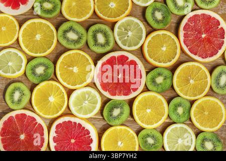 Frame with slice of oranges, lemons, kiwi, grapefruit pattern isolated on wooden background. Flat lay, top view Stock Photo