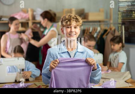 Boy showing stitched fabric during sewing workshop for children Stock Photo