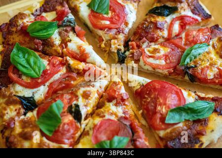 Pizza basil tomatoes: Freshly baked pizza, topped with basil, and tomatoes, served immediately for a flavorful meal. Stock Photo
