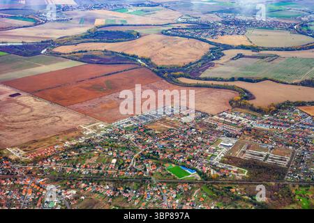 Aerial autumn fields and city of Slovakia, view from flying plane window. Top view shot of slovak countryside, densely populated slovak town with gree Stock Photo