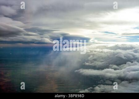 Aerial view of dramatic storm clouds over land, with heavy rain falling from dark sky and sunlight. Dark thunderstorm gray cloud above summer countrys Stock Photo