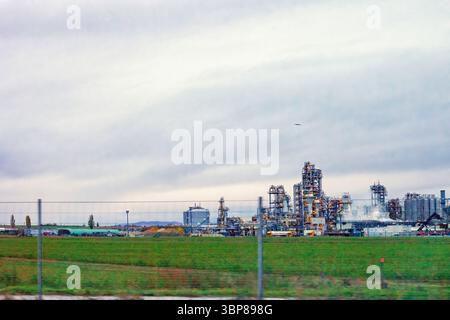 Crude oil refinery plant and green meadow. Summer scenic with fields and factory complex with industrial chimneys, tanks, pipelines, emission in Austr Stock Photo
