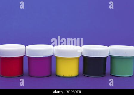Large set of acrylic paint cans in a row. Colorful paints neon blue and violet background with copyspace Stock Photo