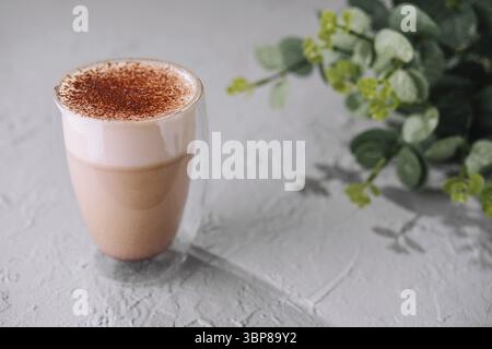 Food, Aromatic milk tea latte topped with spices, served in a clear glass, with a green plant background Stock Photo