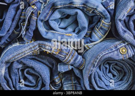 Roll blue denim jeans arranged in stack, background texture. Beauty and fashion clothing concept Stock Photo