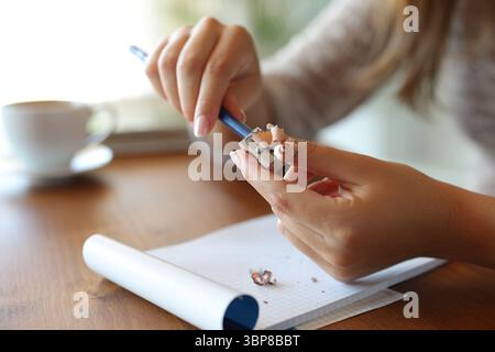 Close up of a woman hands sharpening pencil on a wooden table at home Stock Photo
