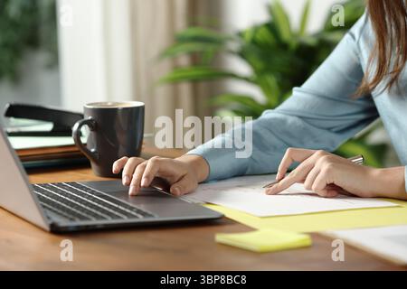 Close up of a woman hands working online checking documents and using laptop on wooden table at office Stock Photo
