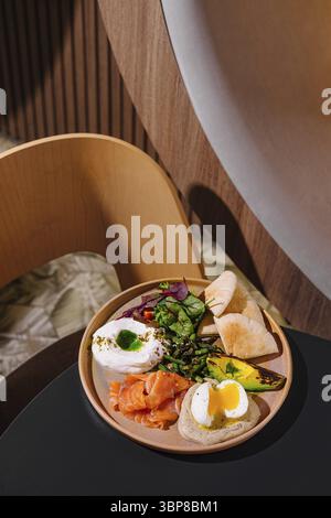 Food, Delicious and healthy breakfast plate combining smoked salmon, poached egg and avocado on a wooden table Stock Photo