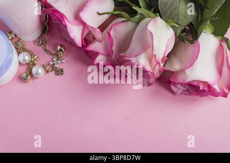 Pink blooming roses and face cream on pastel pink background. Romantic skincare floral frame. Copy space Stock Photo