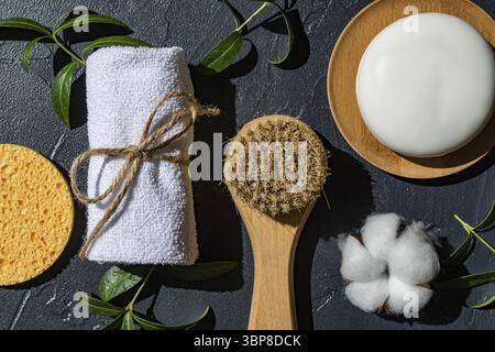 SPA organic natural accessories for face and body treatment with cotton flower and green leaves on black background. Zero waste bathroom essentials, p Stock Photo