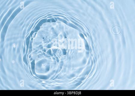 Abstract summer blue background. Transparent clear water surface texture with ripples and splashes. Water waves in sunlight, copy space, top view. Cos Stock Photo