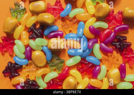 Multi-colored glazed jelly beans sweets on orange paper background Stock Photo