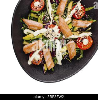 Food, Fresh salmon salad with avocado, tomatoes and sesame seeds in a black bowl, isolated on white background Stock Photo