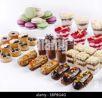 Food, A vibrant assortment of desserts showcases delicious items including macarons, pudding cups, and filled pastries arranged beautifully on a white Stock Photo