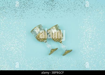 Two empty champagne glasses on blue sparkling background. Festive greeting card with confetti Stock Photo