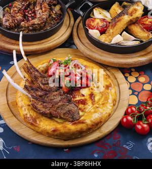 Food, Delicious grilled lamb ribs served on flatbread with fresh tomato and onion salad on a restaurant table Stock Photo