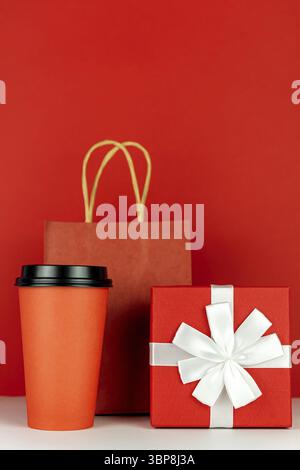 Happy New year 2021 christmas shopping. Gift box, paper craft bag and coffee cup on red background, Monochrome Stock Photo