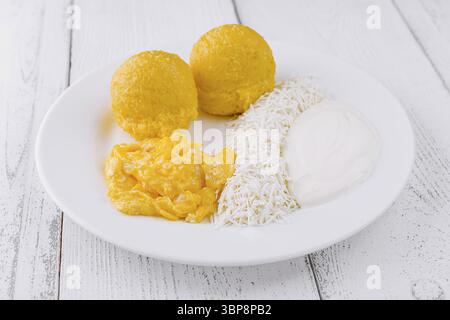 Food, Delicious breakfast with scrambled eggs, corn fritters, coconut flakes and sour cream on white plate Stock Photo