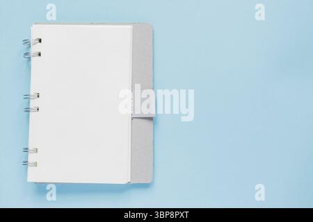 Clean spiral note book for notes and messages on blue background. Minimal business flat lay Stock Photo