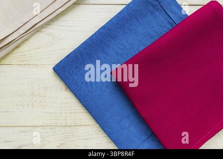 Top view of cloth napkins of beige, blue and burgundy colors on rustic white background Stock Photo