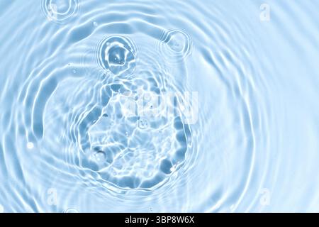 Abstract summer blue background. Transparent clear water surface texture with ripples and splashes. Water waves in sunlight, copy space, top view. Cos Stock Photo