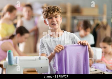 Boy showing stitched fabric during sewing workshop for children Stock Photo